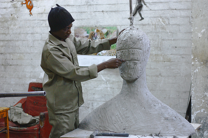 man sculpting head statue