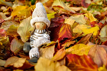 female wearing white coat doll on leaves