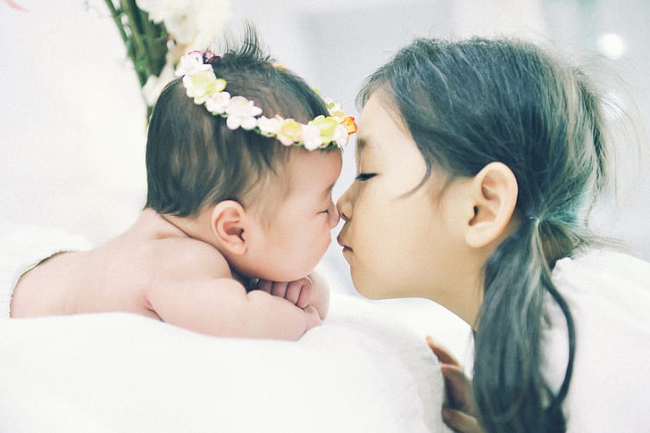 photo of girl kissing a baby