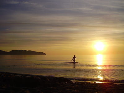 person walking in water over golden hour