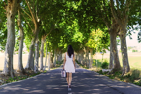 woman in white dress walking on road at daytime