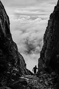 Silhouette of Man Walking Between Two Cliff