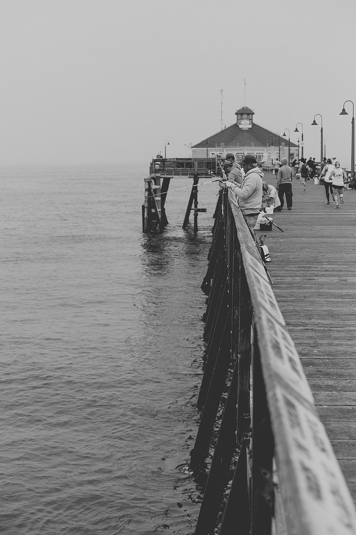 people on wooden dock grayscale photo