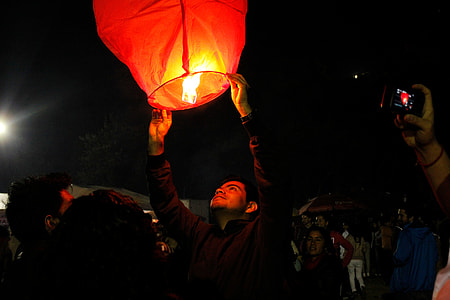 man in b lack jacket holding sky lantern