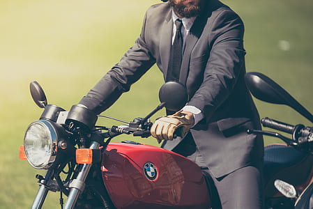 man in black formal suit riding red BMW standard motorcycle