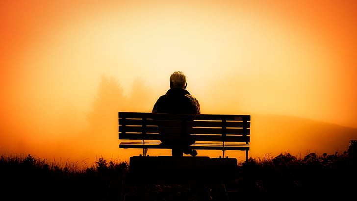 man sitting on a bench taken on sunset