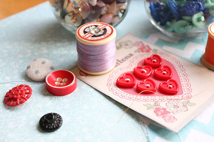photo of purple sewing thread beside red cloth button