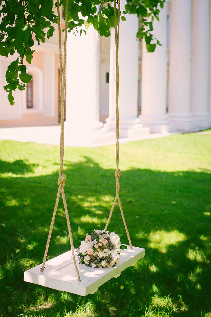 white wooden swing with bouquet of white and pink flowers