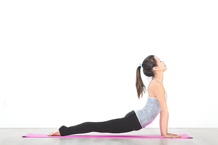 woman wearing grey tank-top doing yoga near white wall