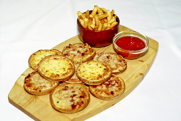 assorted-flavor of pizza with fries and ketchup on brown wooden tray