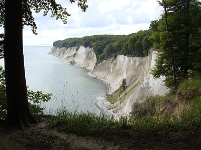 gray cliff beside body of water