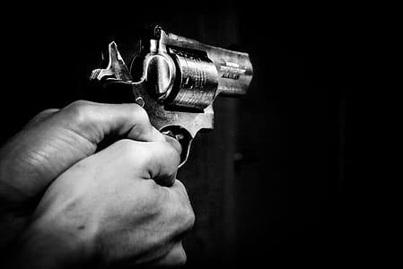 grayscale photo of person holding revolver pistol