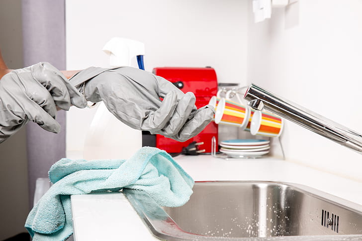 person wearing gloves near stainless steel faucet