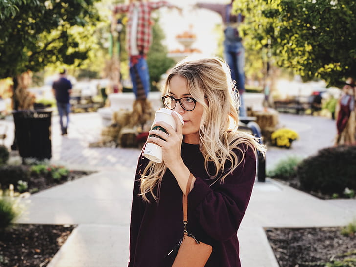 woman wearing purple knit sweater holding white plastic travel cup during daytime