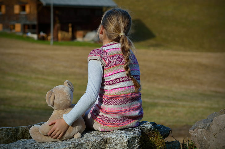 girl wearing pink and white tribal vest sitting on the rock