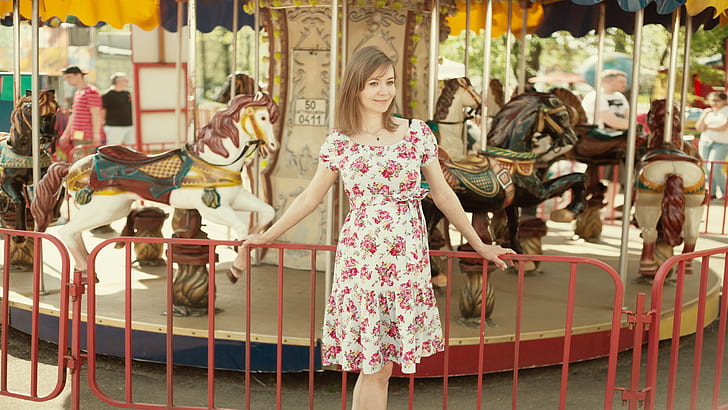 woman in white and pink floral dress near carousel