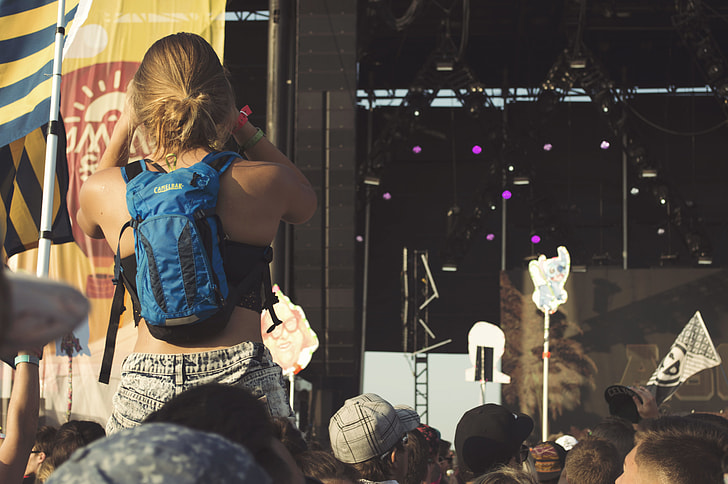 woman piggyback ride wearing blue backpack near stage