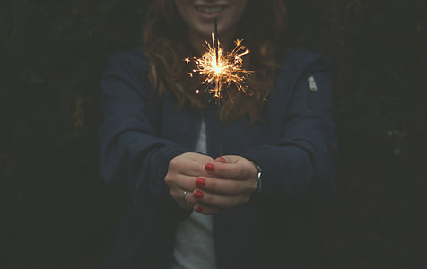 image contains woman holing lit sparkler