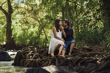 man and woman sitting on tree roots during daytime