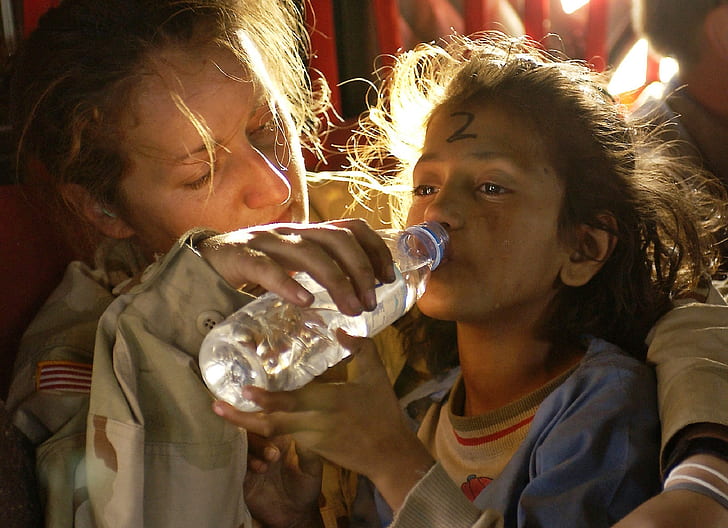 woman helping the girl drinking water on plastic bottle