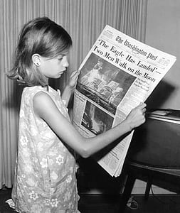 girl holding newspaper near window curtain