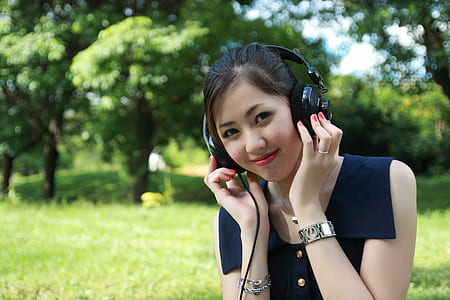 woman wearing sleeveless shirt using black headphones