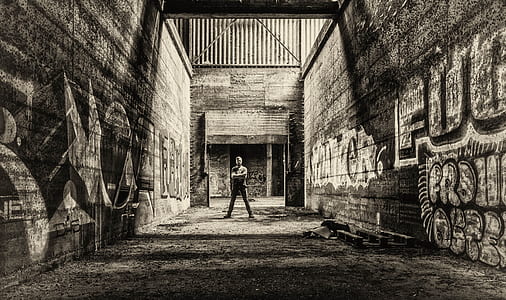 man standing between graffiti painted walls