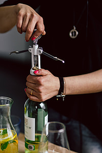 Hands opening wine bottle with corkscrew