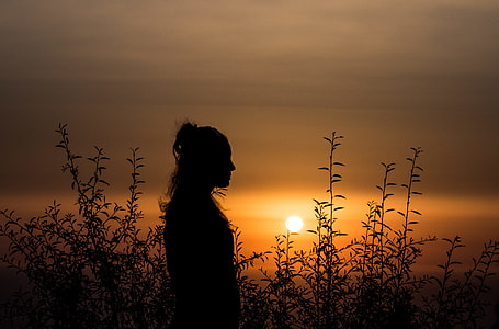 person standing in tall grass field during sunset