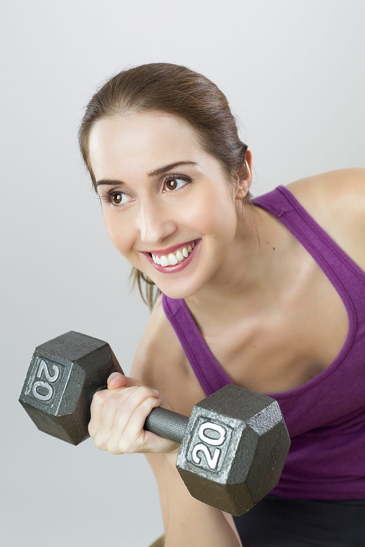 woman in purple tank top lifting dumbbell