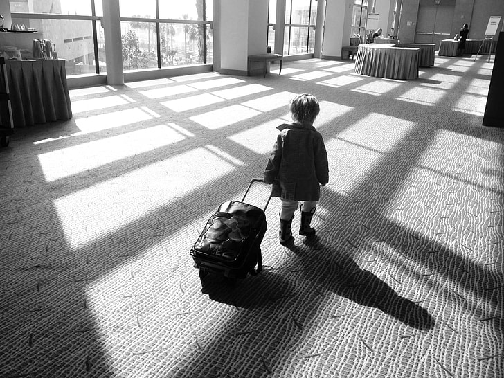 boy with luggage walking inside room