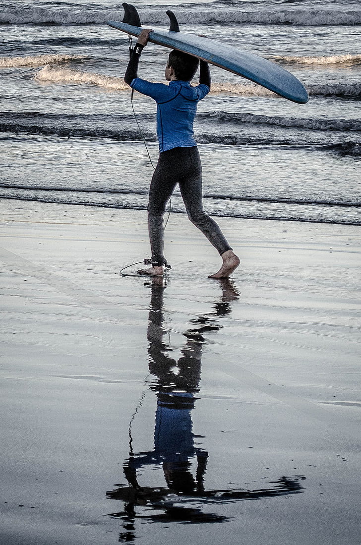 person carrying blue surfboard