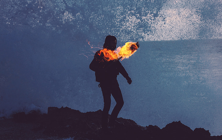 person standing on the mountain holding torch with fire