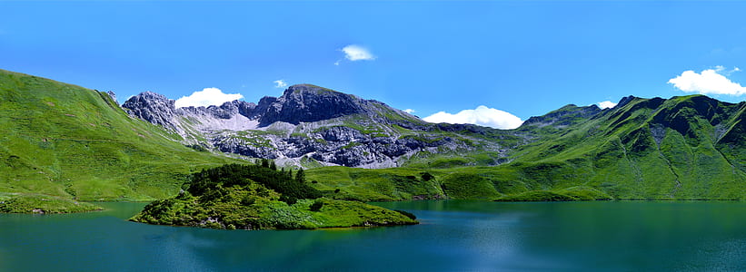 body of water beside green mountain