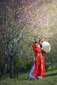 woman wearing red traditional dress standing on grass fielkd