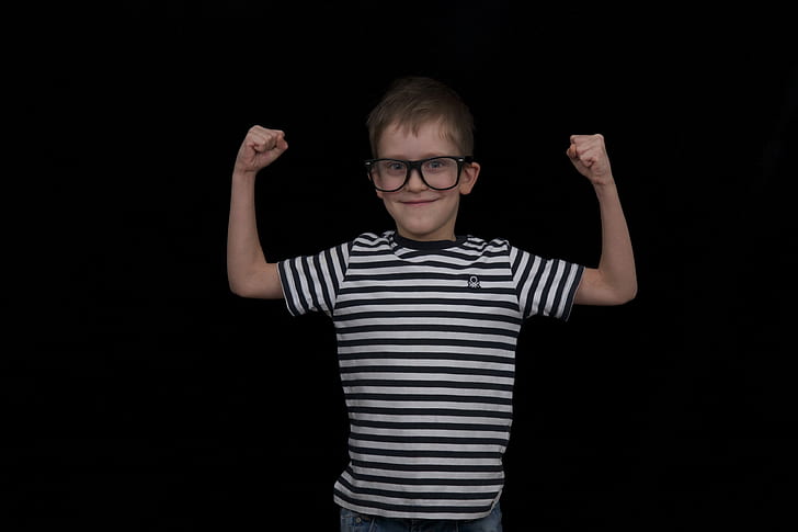 boy raising his hand wearing eyeglasses