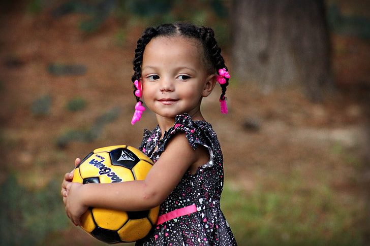 girl hugging yellow and black soccer ball