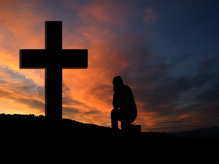 silhouette of person sitting in front of cross