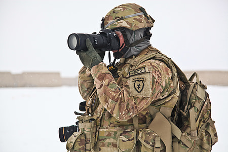 soldier wearing brown and green camouflage uniform looking through DSLR camera