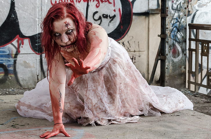 woman in white bridal gown full of fake blood crawling on floor