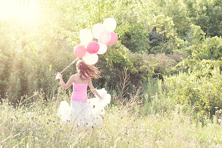 woman holding white and pink balloons