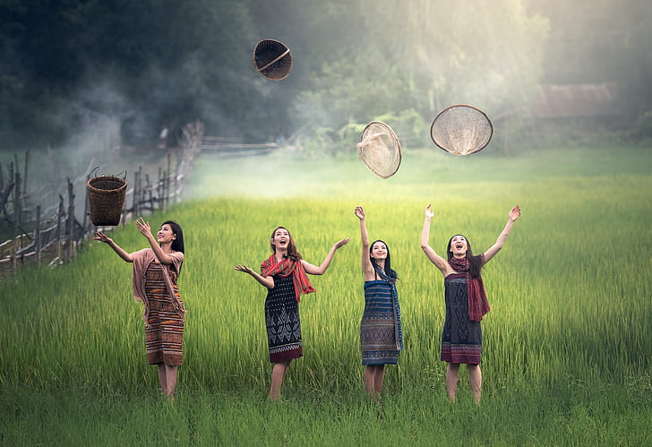 four women on rice field throwing baskets at daytime