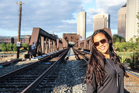 woman wearing black scoop-neck long-sleeved shirt on train tracks during daytime