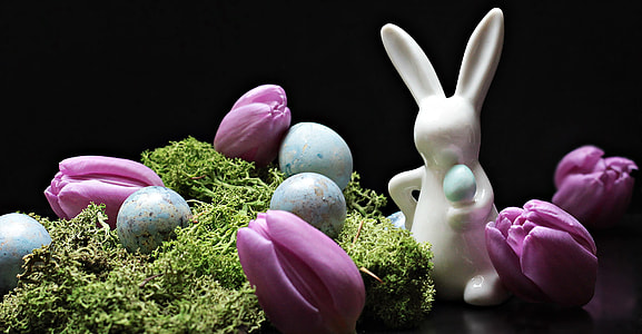 white ceramic rabbit figurine near purple tulips and blue eggs