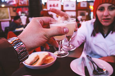 Man Wearing Silver Link Watch Holding a Glass Containing White Liquid in Front of a Woman