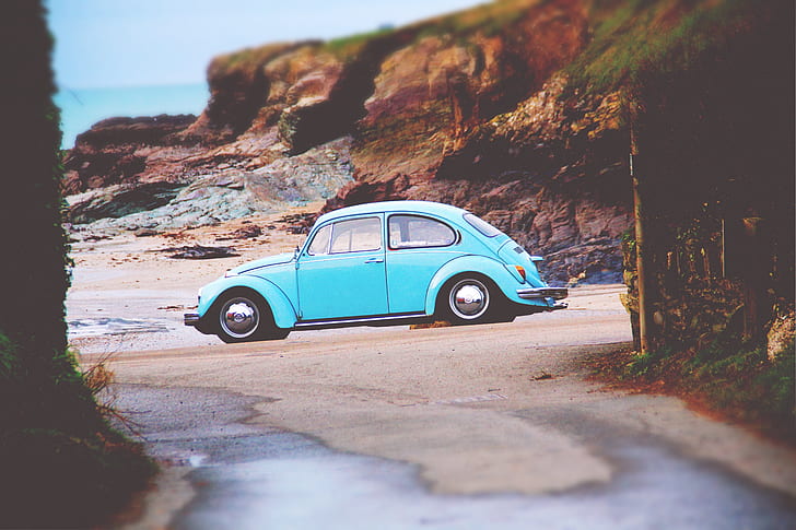 teal Volkswagen Beetle parked on seashore at daytime