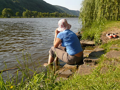 person sitting near river during daytime