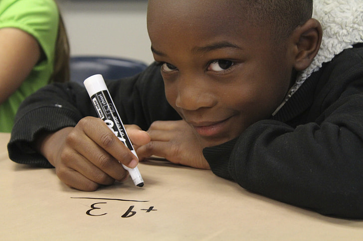 boy wearing black parka coat writing with marker