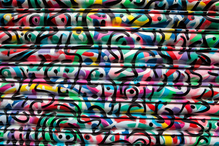 Vibrantly coloured paint swirls on a metal shop shutter