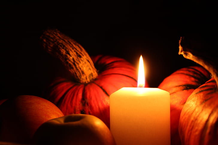 white votive candle beside pumpkins